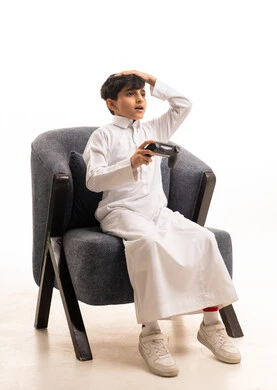 طفل سعودي بالثوب التقليدي يلعب ألعاب الفيديو