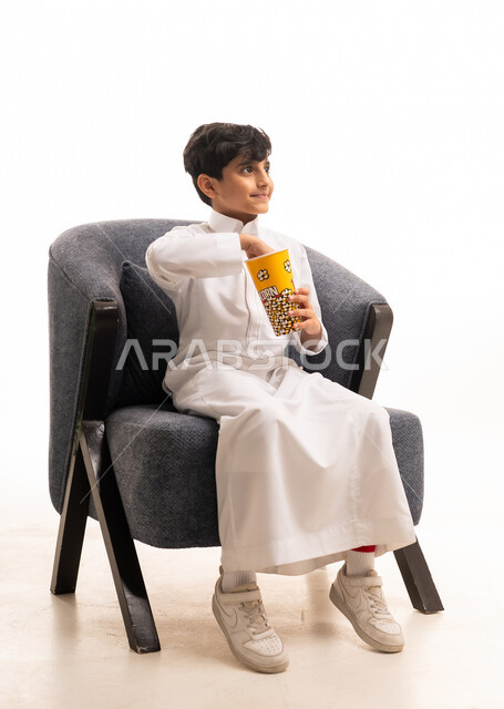 طفل سعودي بالثوب الأبيض يأكل الفشار في الاستوديو