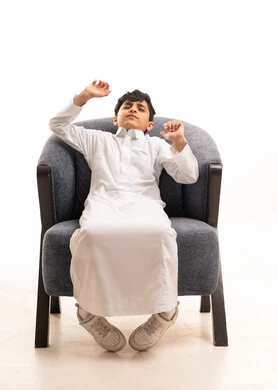 Saudi Boy in White Thobe Sitting in Armchair