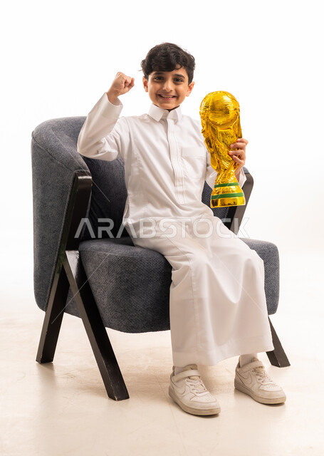 طفل سعودي بالثوب يحمل كأس العالم الذهبي