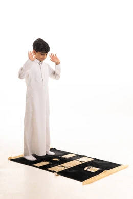Saudi Boy Praying in White Thobe on Prayer Mat
