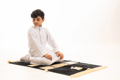 Saudi Boy in White Thobe Praying on Rug