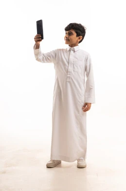 ولد سعودي بالثوب التقليدي يستخدم الهاتف الذكي