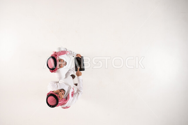Saudi Men in Traditional Dress with Tablet Overhead