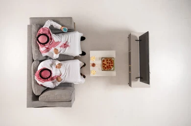 Saudi Men Watching TV with Pizza and Popcorn Overhead