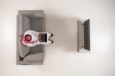 Saudi Man Using Laptop on Sofa Overhead View