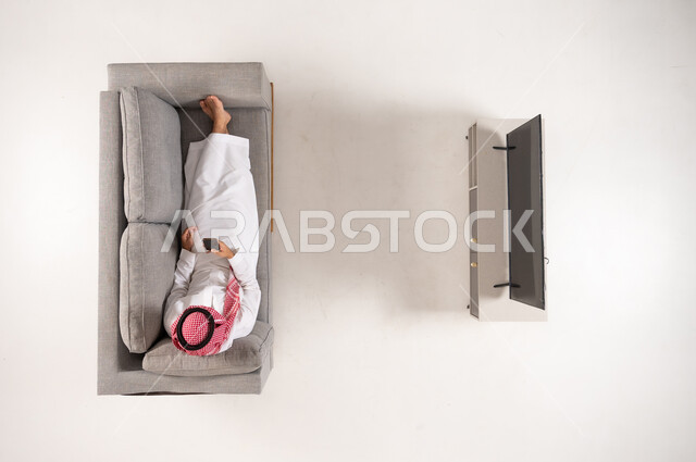 رجل سعودي يستخدم الهاتف على الأريكة منظور علوي