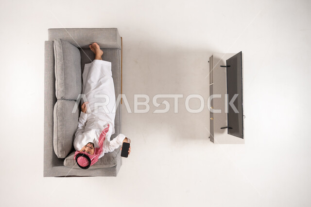 Saudi Man on Sofa with Smartphone Top View