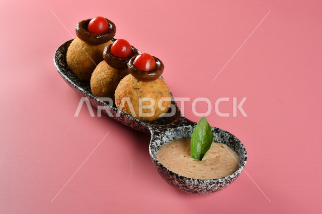 A plate of stuffed potato balls with a side of sauce, delicious meals, Arab restaurants, oriental Arab food, Ramadan food, Ramadan breakfast, delicious Arab food, recipes and food dishes