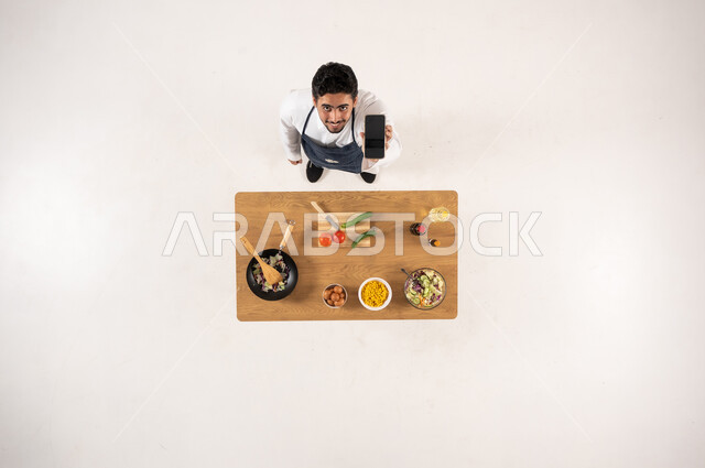 رجل سعودي بالثوب مع هاتف ذكي منظور علوي