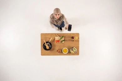 Arab Woman in Hijab Holding Smartphone by Kitchen Table