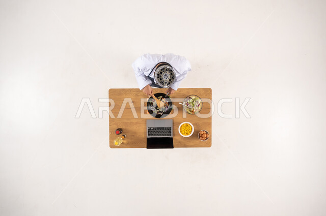 شيف سعودي يطبخ مع كمبيوتر محمول منظر علوي