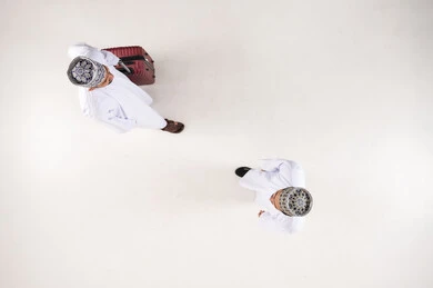 Omani Men in Traditional Dress Walking with Suitcase