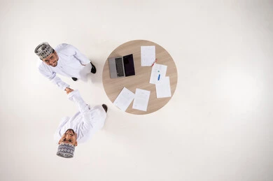 Omani Men Shaking Hands at Meeting Table Overhead