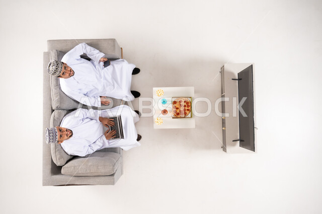 Omani Men in Traditional Dress Using Laptop at Home