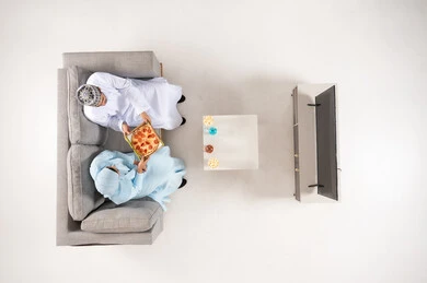 Omani Couple Eating Pizza on Sofa Top View