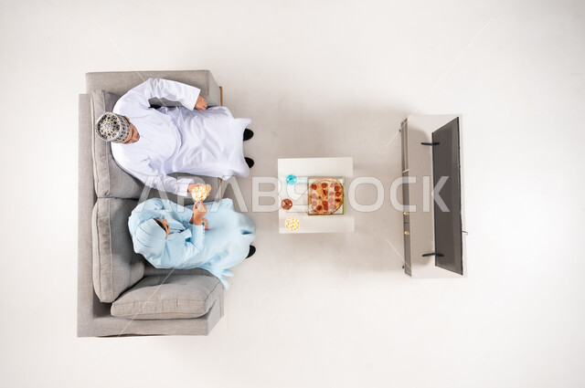 رجل وطفل عمانيان يجلسان على الأريكة من منظور علوي