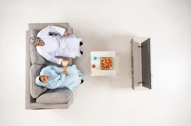 Omani Couple Eating Pizza on Sofa Top View