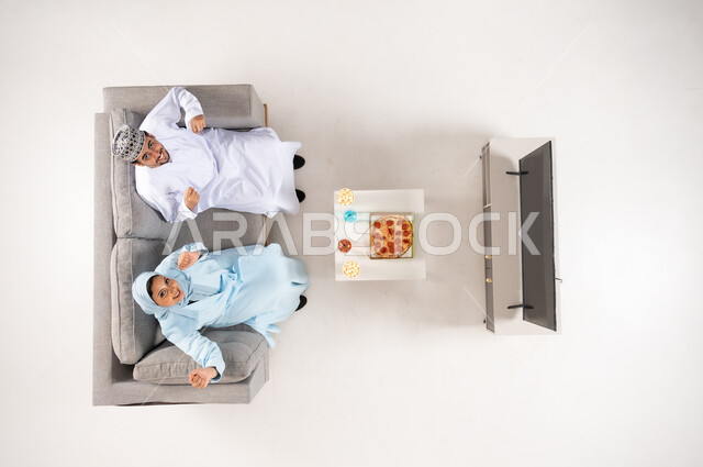 رجل وطفل عمانيان يشجعان على الأريكة لقطة علوية