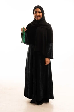 امرأة سعودية بالعباءة السوداء تحمل سبحة خضراء