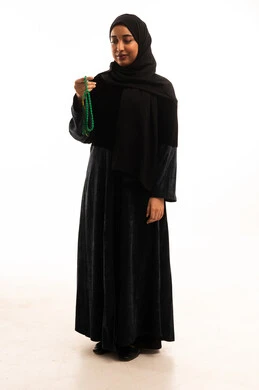 امرأة سعودية بعباءة سوداء تمسك مسبحة خضراء