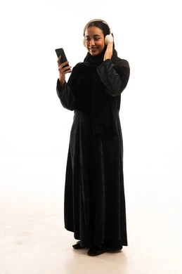Saudi Woman in Abaya with Headphones and Smartphone Saudi Woman in Abaya with Headphones and Smartphone