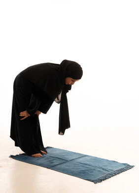 امرأة عربية في وضعية الركوع أثناء الصلاة بالعباءة