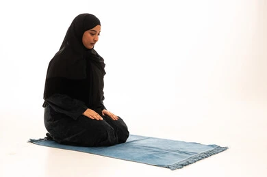 Muslim Woman Praying on Mat in White Studio