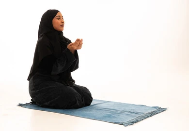 امرأة عربية مسلمة تدعو بالعباءة السوداء على خلفية بيضاء