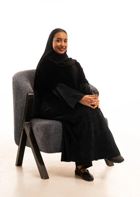 امرأة سعودية بالعباءة السوداء تجلس على كرسي استوديو