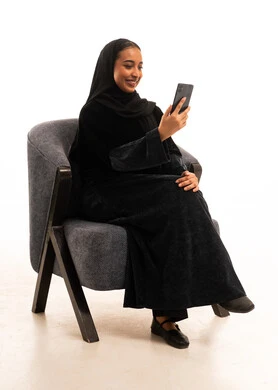 امرأة سعودية بالعباءة السوداء تستخدم الجوال