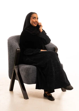 Saudi Woman in Abaya Using Smartphone on Armchair
