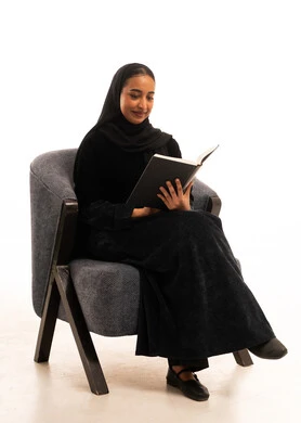 امرأة سعودية بالعباءة السوداء تقرأ كتاباً في استوديو