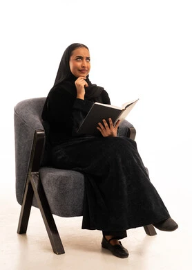امرأة سعودية بالعباءة تقرأ كتاباً في الاستوديو