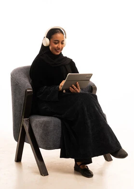 Saudi Woman in Abaya Using Tablet with Headphones