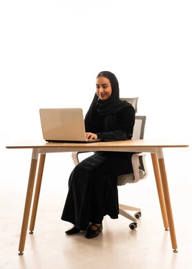 امرأة سعودية تستخدم الكمبيوتر المحمول في مكتب بخلفية بيضاء