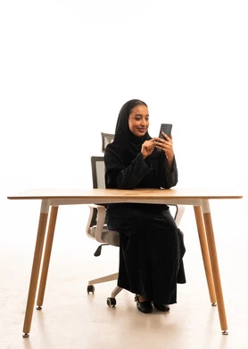Saudi Woman in Abaya Using Smartphone at Desk
