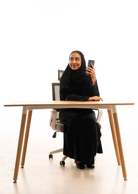 Saudi Woman with Smartphone at Office Desk