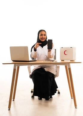 Saudi Female Doctor Pointing to Smartphone at Desk