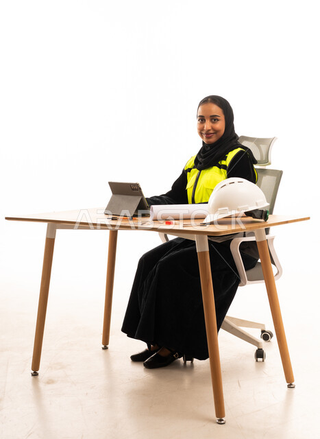 مهندسة سعودية خلف مكتب العمل مع أدوات السلامة