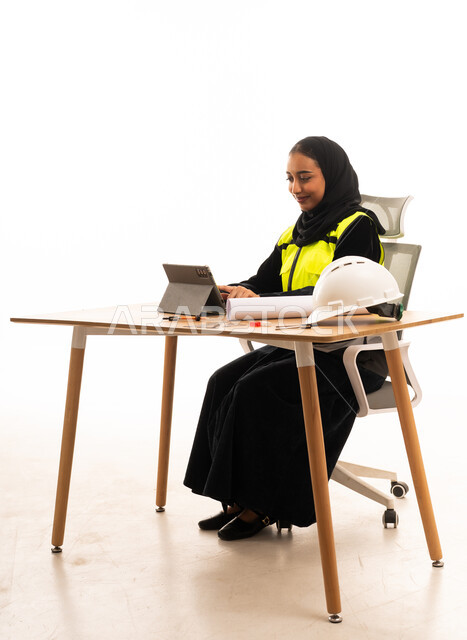 مهندسة سعودية تعمل على جهاز لوحي ومخططات هندسية