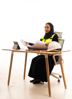 Saudi Female Engineer with Blueprints at Office Desk