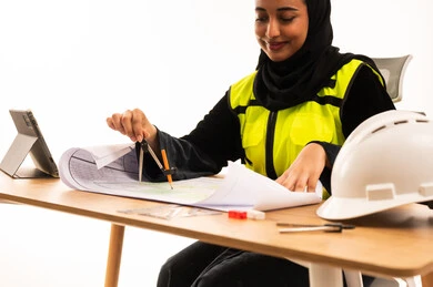 مهندسة سعودية تعمل على مخطط هندسي في المكتب