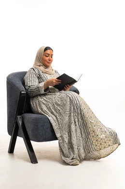 امرأة عربية تقرأ كتاباً على كرسي في استوديو خلفية بيضاء