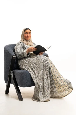 امرأة سعودية بالزي التقليدي تقرأ كتاباً