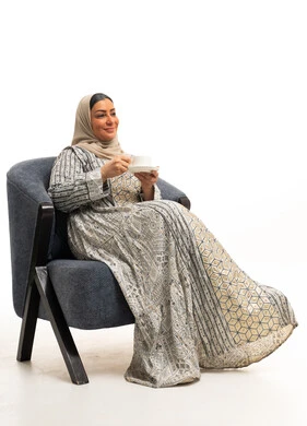 امرأة عربية بجلابية تقليدية تجلس مع فنجان شاي