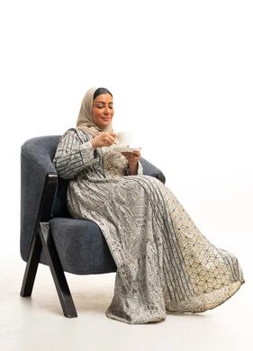 امرأة سعودية بالعباءة تشرب القهوة على كرسي