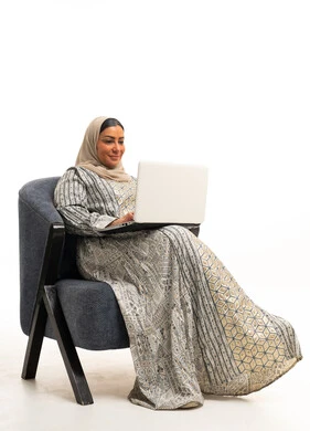 امرأة سعودية بالحجاب تستخدم لابتوب على كرسي