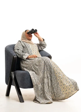 سيدة سعودية مع منظار على كرسي أزرق