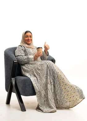 امرأة سعودية بالجلابية التقليدية تحمل كوب قهوة